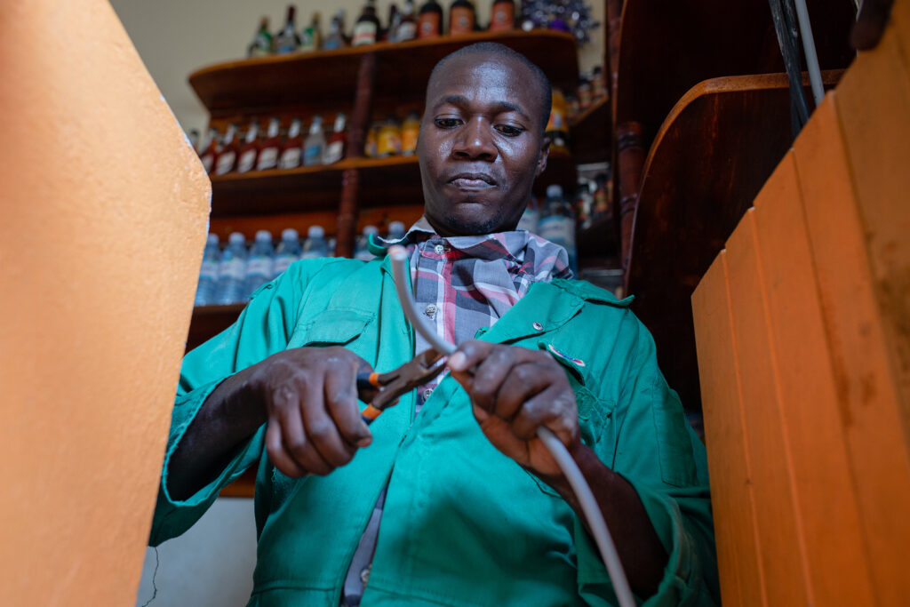 FRES Uganda technician Mugume Anthony installing a solar system at a pub